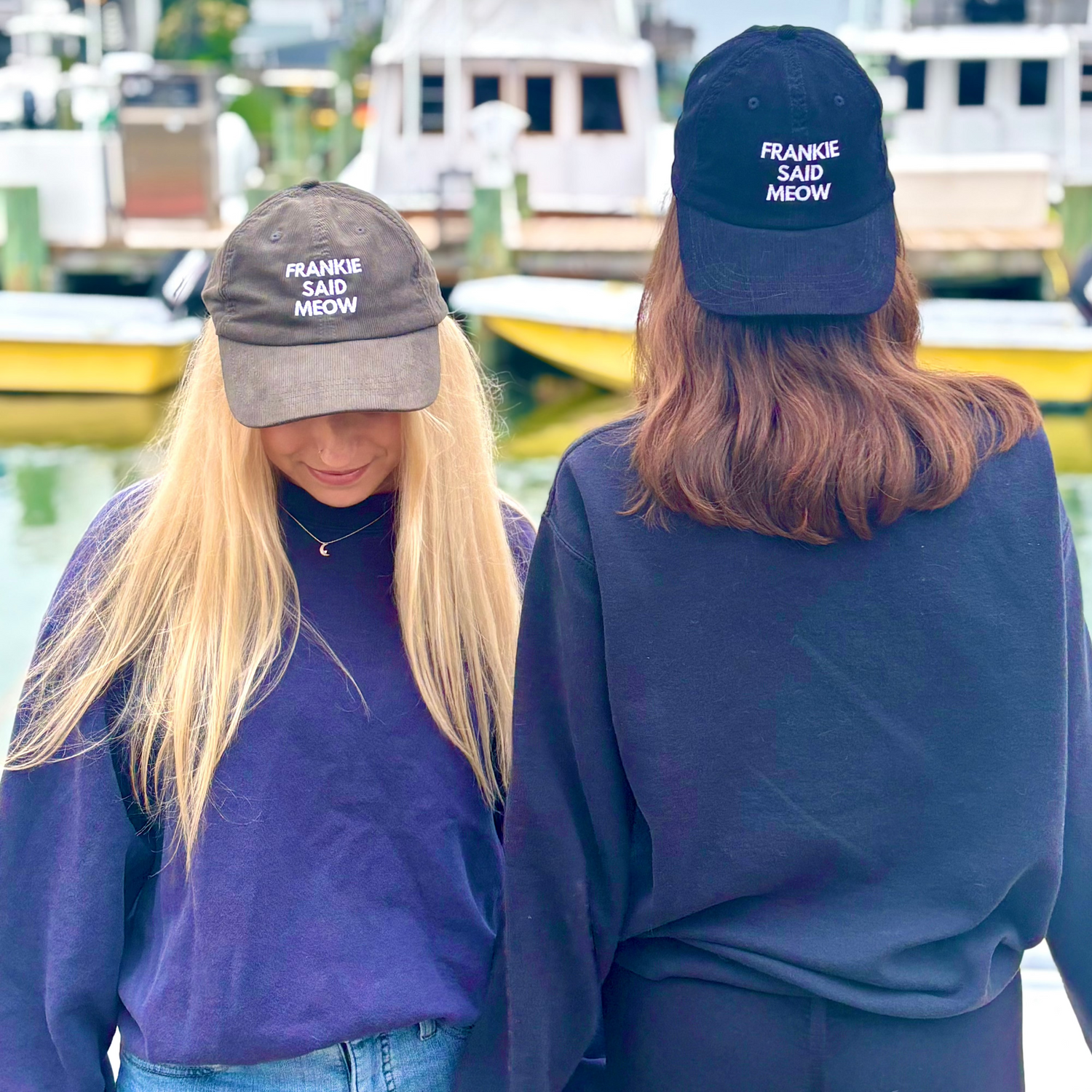 Two girls on dock wearing Frankie Said Meow caps