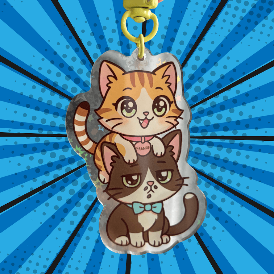 Double-sided acrylic keychain of Coqui and Frankie chibi, holographic stars, gold clasp.