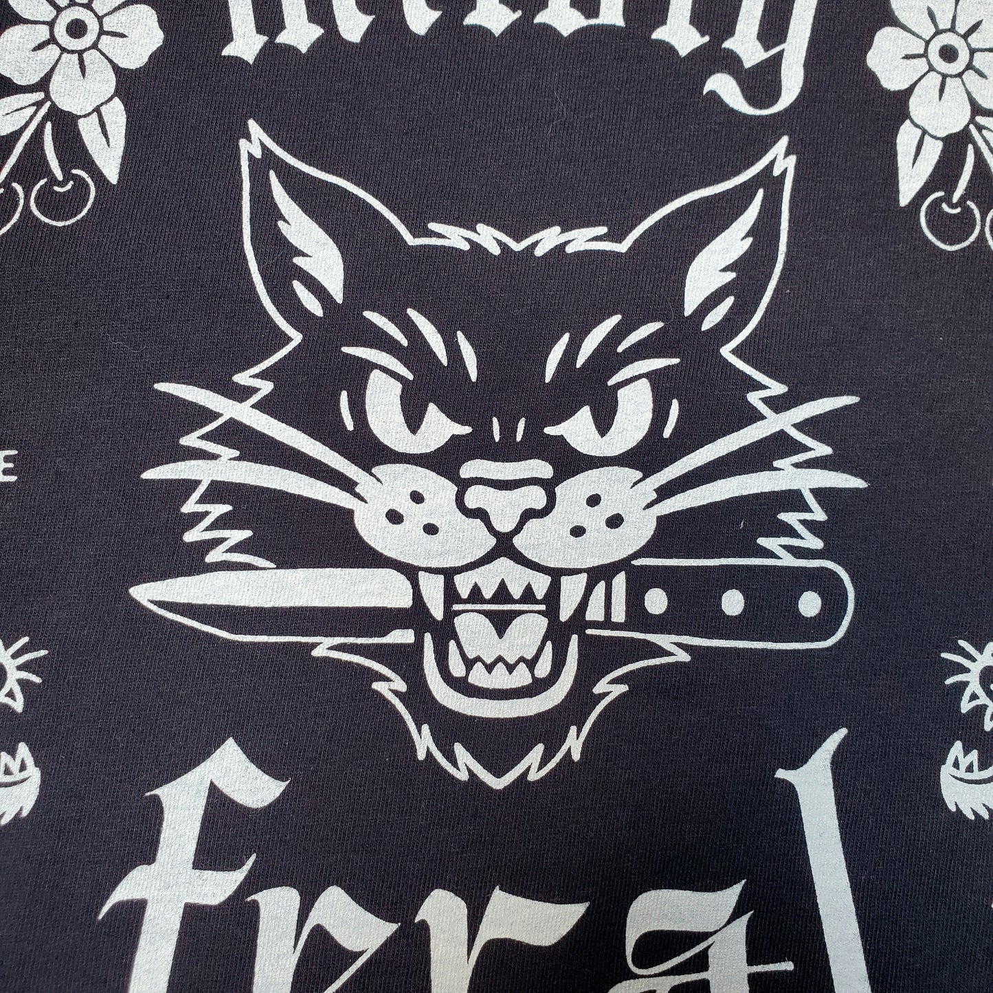 Black Comfort Colors t-shirt featuring a white vintage tattoo-style cat graphic with the words “mildly feral” — Frankie Said Meow limited run design printed by Cracked Ego in Austin, TX.