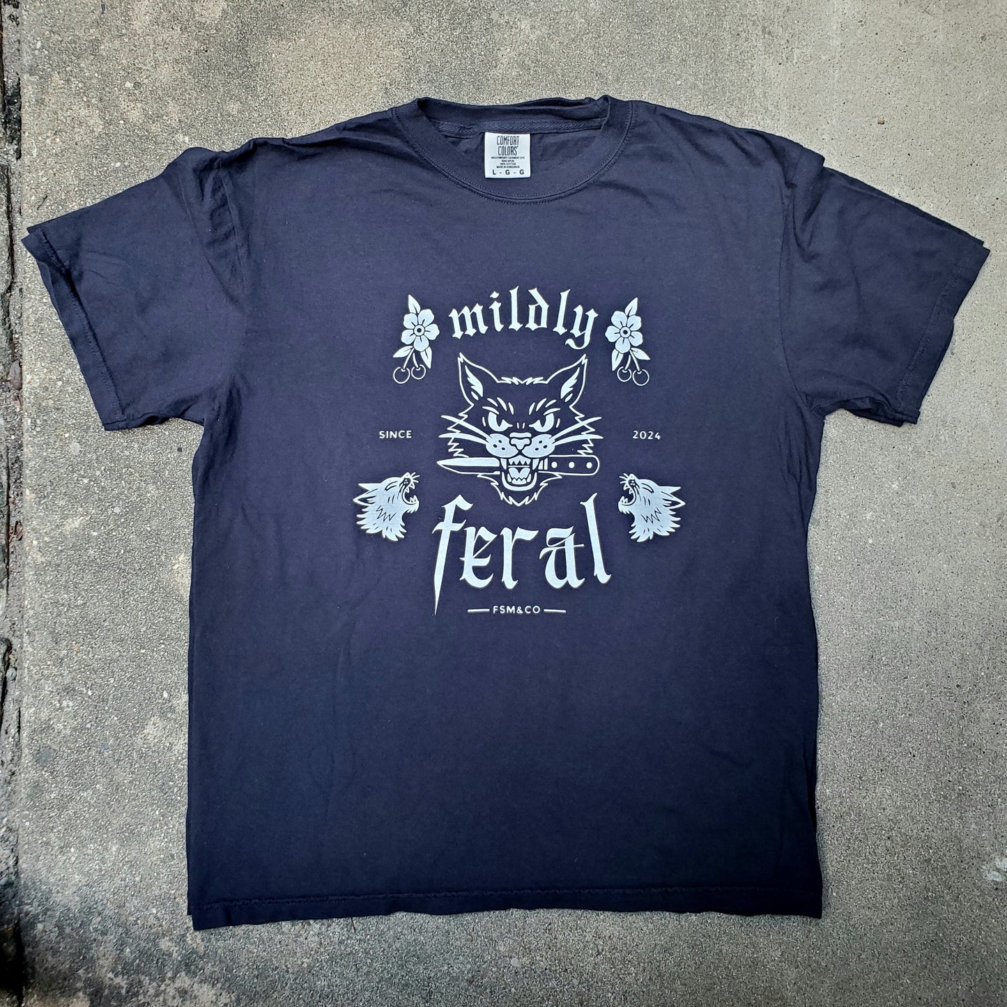 Black Comfort Colors t-shirt featuring a white vintage tattoo-style cat graphic with the words “mildly feral” — Frankie Said Meow limited run design printed by Cracked Ego in Austin, TX.