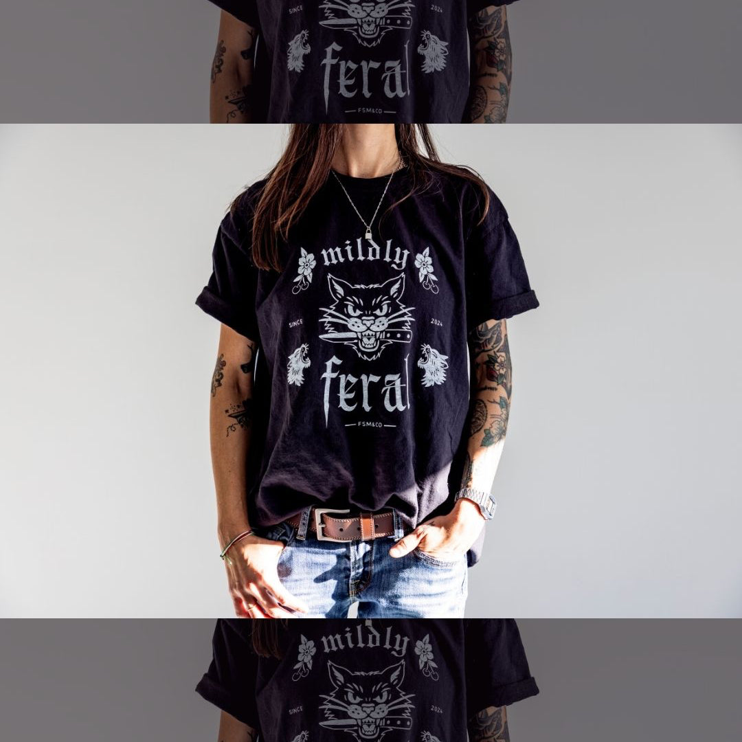 Person wearing a black t-shirt with 'mildly feral' screen print design by Frankie Said Meow and Cracked ego. 