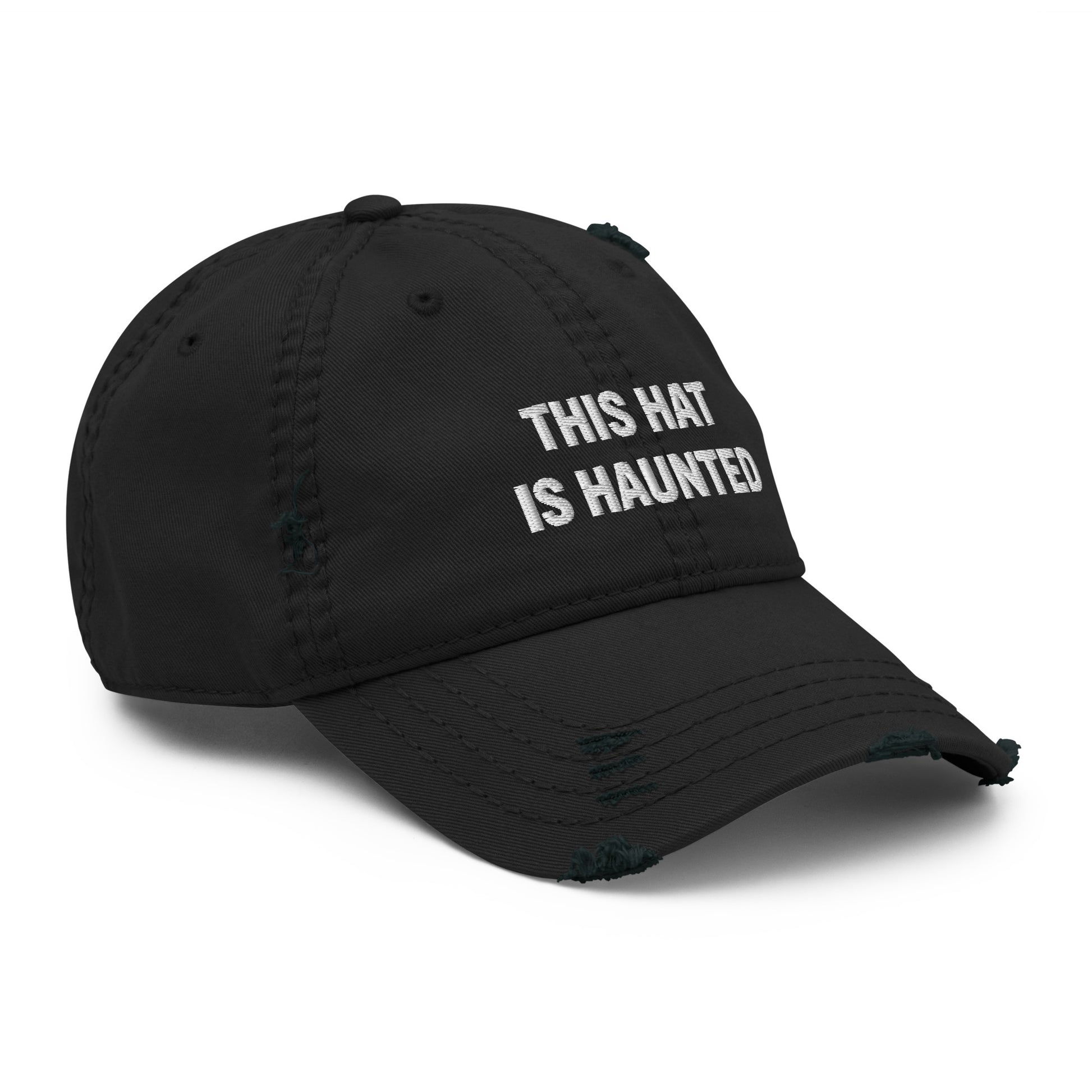 Distressed dad hat in black with white embroidered text reading “this hat is haunted.”
