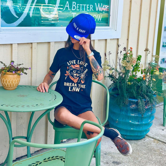 Girl with tattoos wearing vintage cowboy cat shirt with text "Live love break the law"
